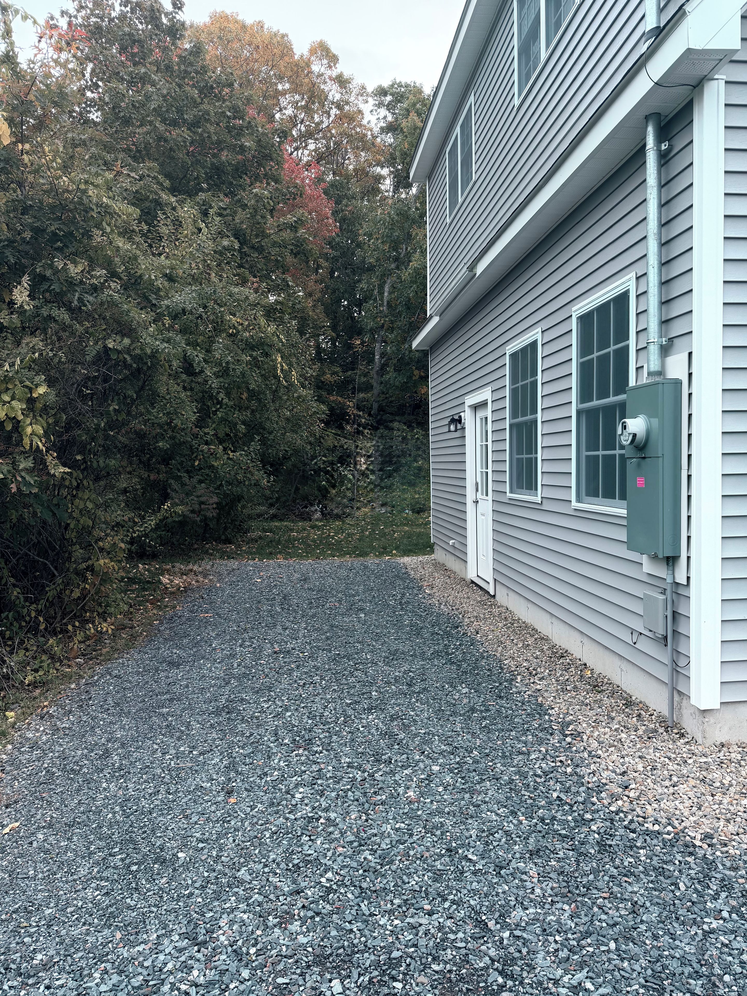 A house with a gravel driveway and a utility box near the entrance.