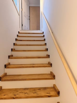 A wooden staircase with a handrail, leading to a door at the top. - Harbor View Loft Walk to town Cozy one bed open studio in Boothbay Harbor  (Boothbay Harbor)