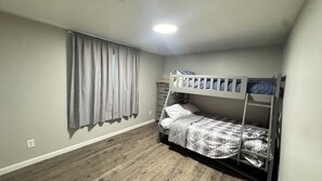 Ein Zimmer mit einem Etagenbett, einem Schminktisch und einem Fenster mit Vorhängen.