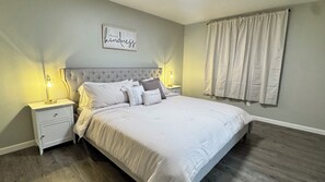 Ein Schlafzimmer mit einem großen Bett, zwei Nachttischen inklusive Lampen, einer Kopfteil und einem an der Wand befestigten Schild.