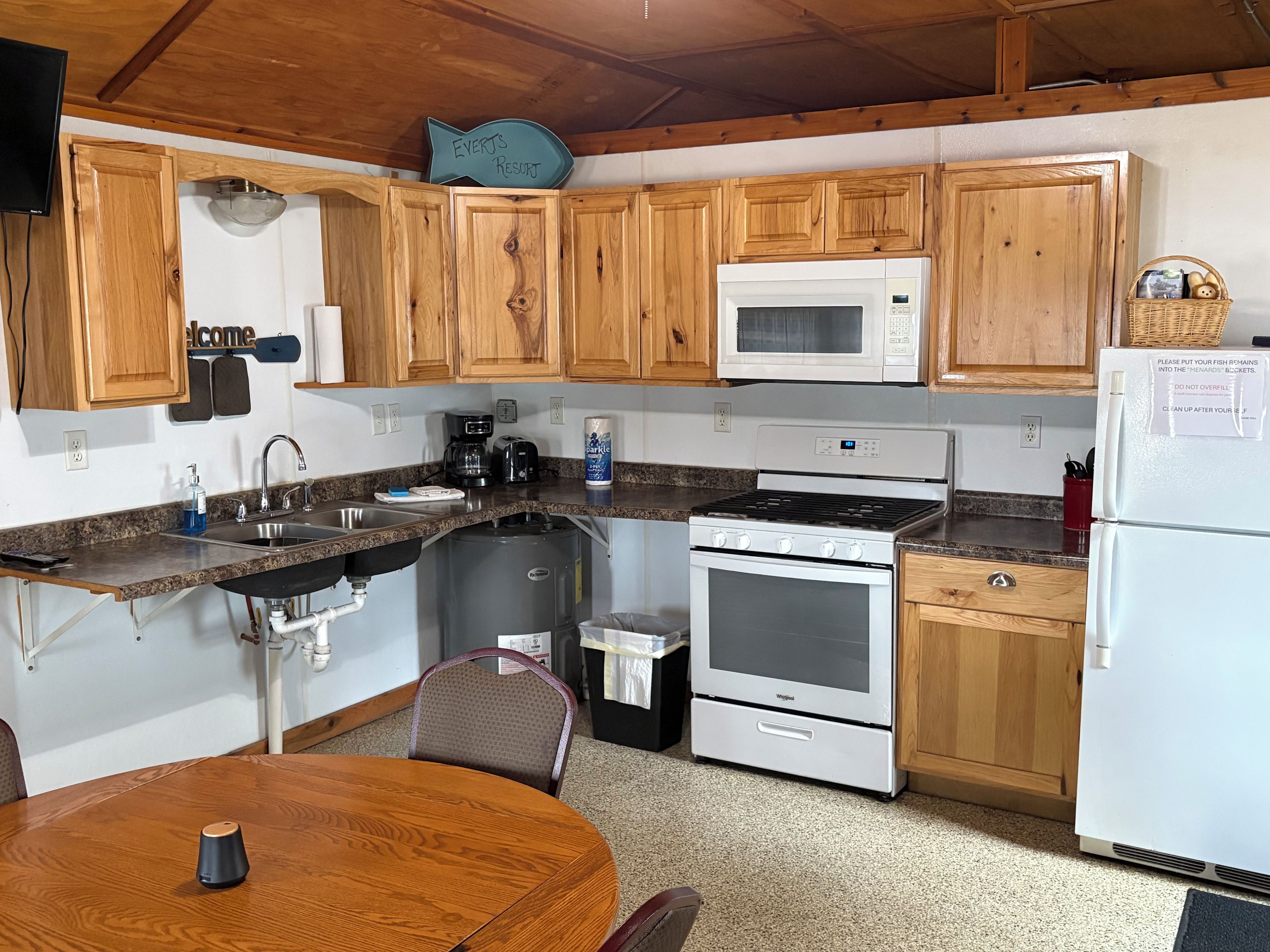 A compact kitchen with wooden cabinets, a microwave, a stove, and a refrigerator.