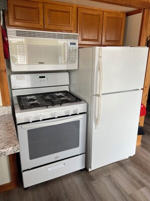 Una cocina equipada con microondas, estufa, horno y refrigerador.