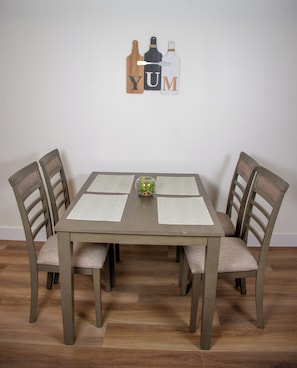 Ein Esstisch mit vier Stühlen, zwei Platzsets und einer kleinen Vase mit einer Pflanze.