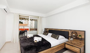Ein modernes Schlafzimmer mit einem großen Bett, einem Holz-Kopfende und einem Nachttisch mit Lampe.
