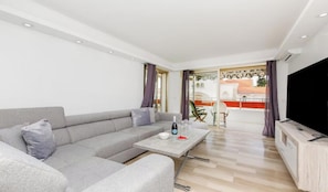 Ein modernes Wohnzimmer mit einem grauen Sofa, einem Couchtisch und einem Flachbildfernseher.