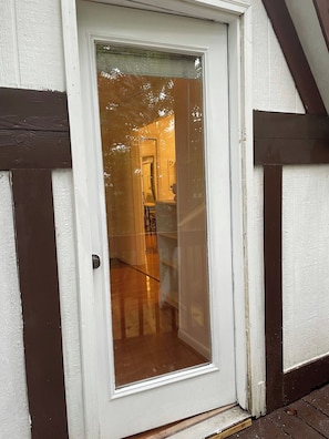 A white door with a glass panel, a wooden floor, and a dark brown trim. - Magnolia Cottage at Saluda River Farms (Greenville)
