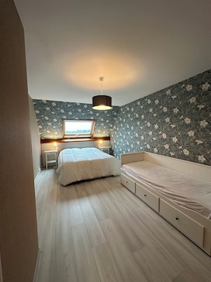 Une chambre à coucher avec un lit, des tables de chevet, une fenêtre et un luminaire au plafond.