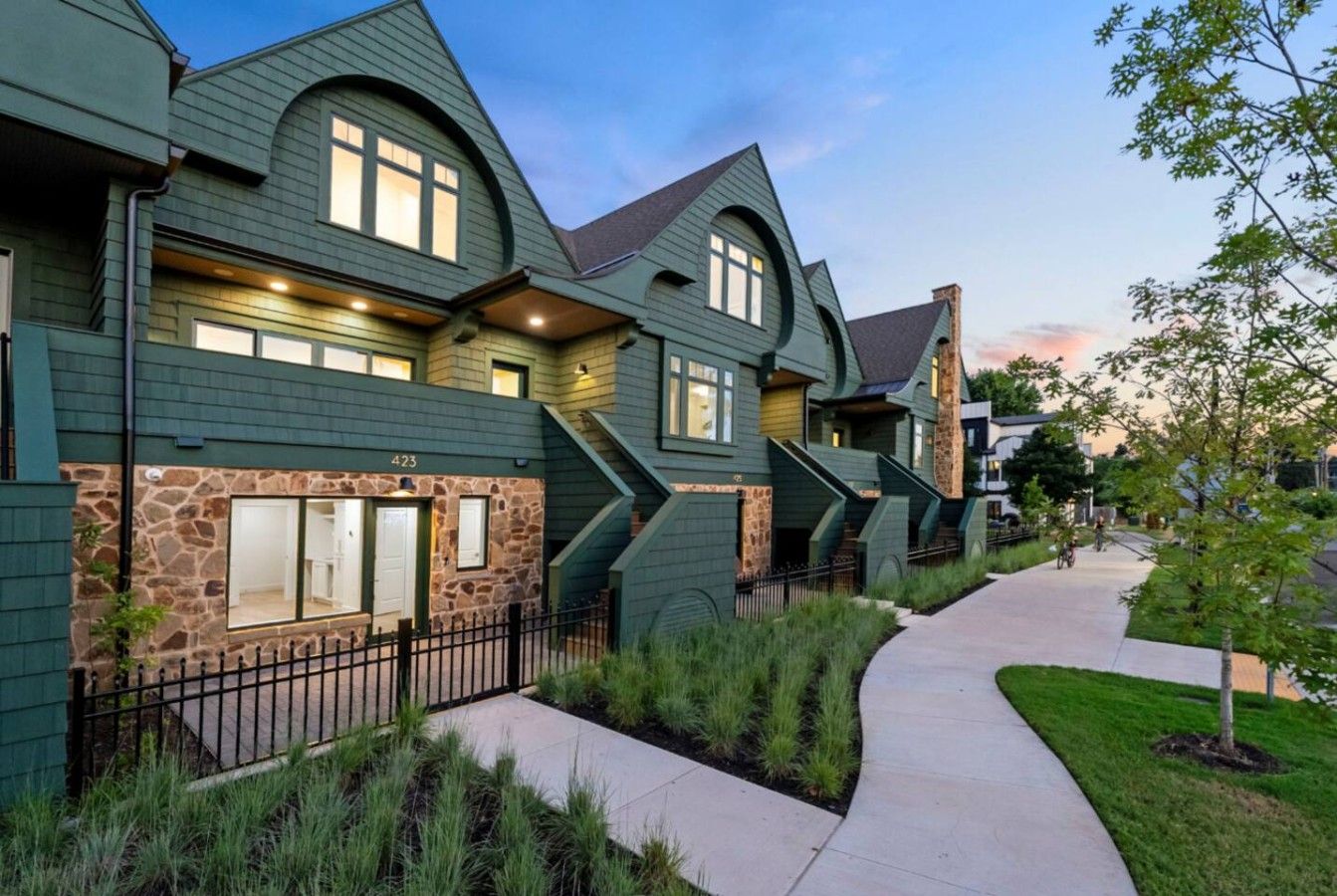 A row of modern houses with a stone facade, a paved walkway, and a well-maintained lawn.