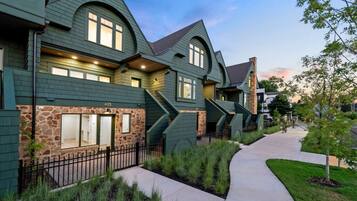 A row of modern houses with a stone facade, a paved walkway, and a well-maintained lawn.