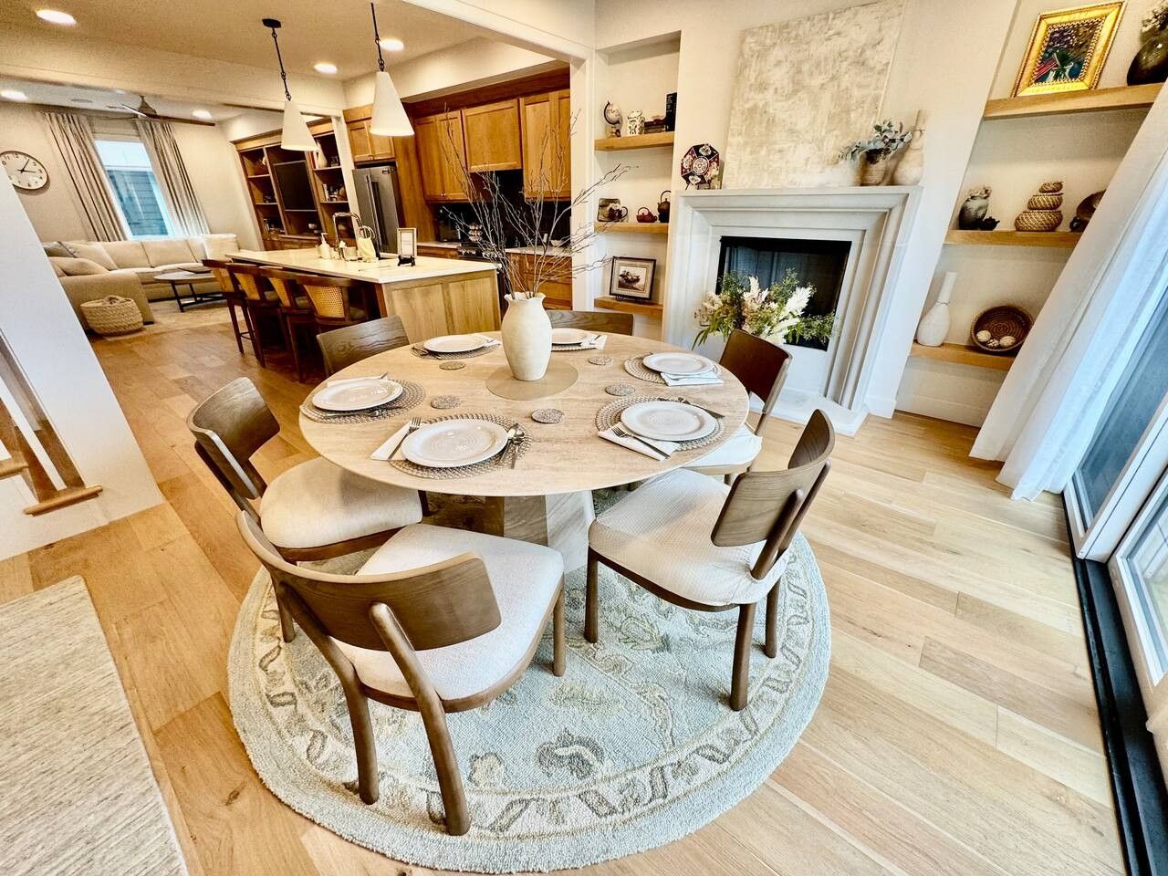 A dining area with a round table set for six, surrounded by chairs.