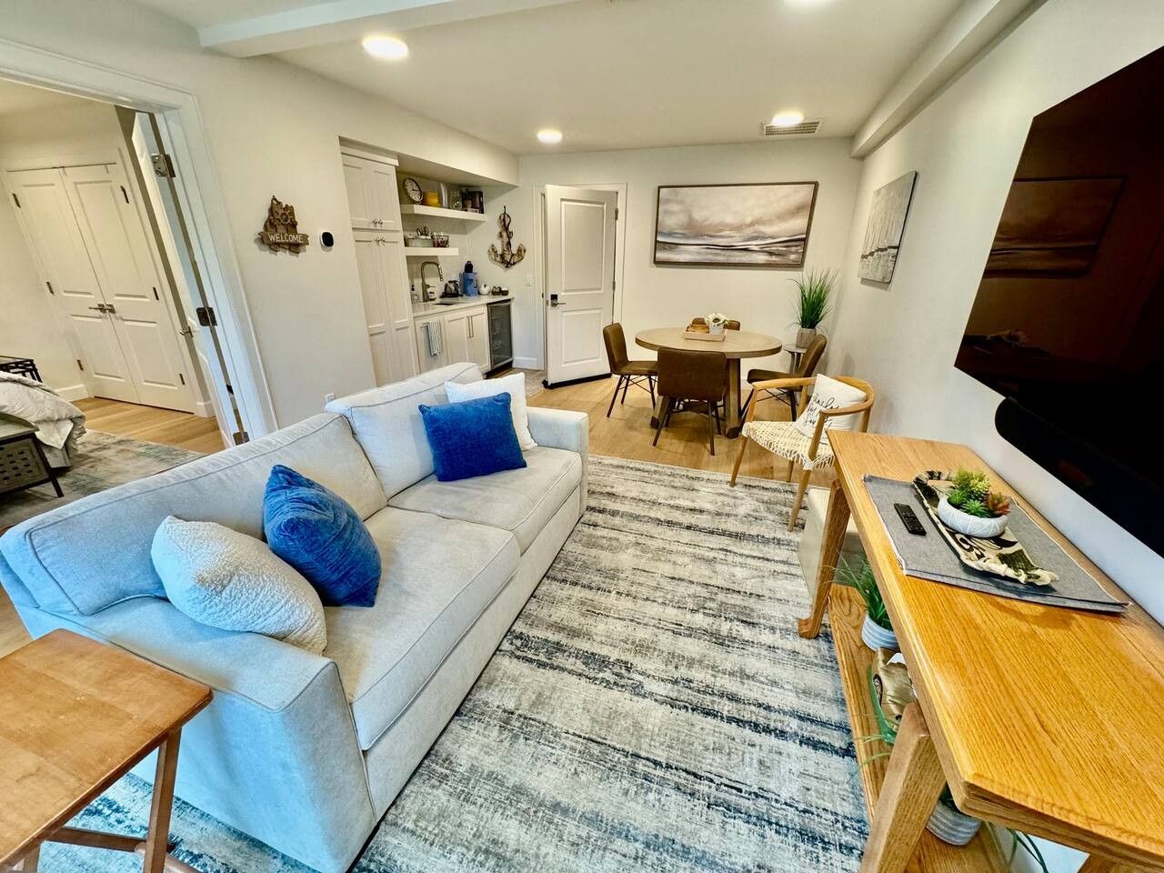 En moderne stue med sofa, sofabord og et spiseområde med stole og bord.