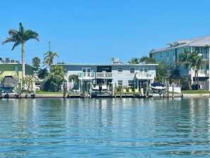 Propiedad frente al agua con muelle, un barco y un edificio con varios balcones.