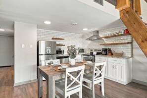 Una cocina moderna con armarios blancos, una mesa de comedor de madera y un horno empotrado.