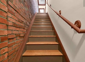 Un escalier en bois avec une rampe, qui monte.