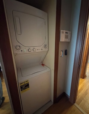 Une buanderie équipée d’un lave-linge blanc, d’un sèche-linge et d’une étiquette indiquant la consommation énergétique.