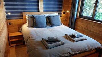 Una cama con cabecera de madera, almohadas y una manta.