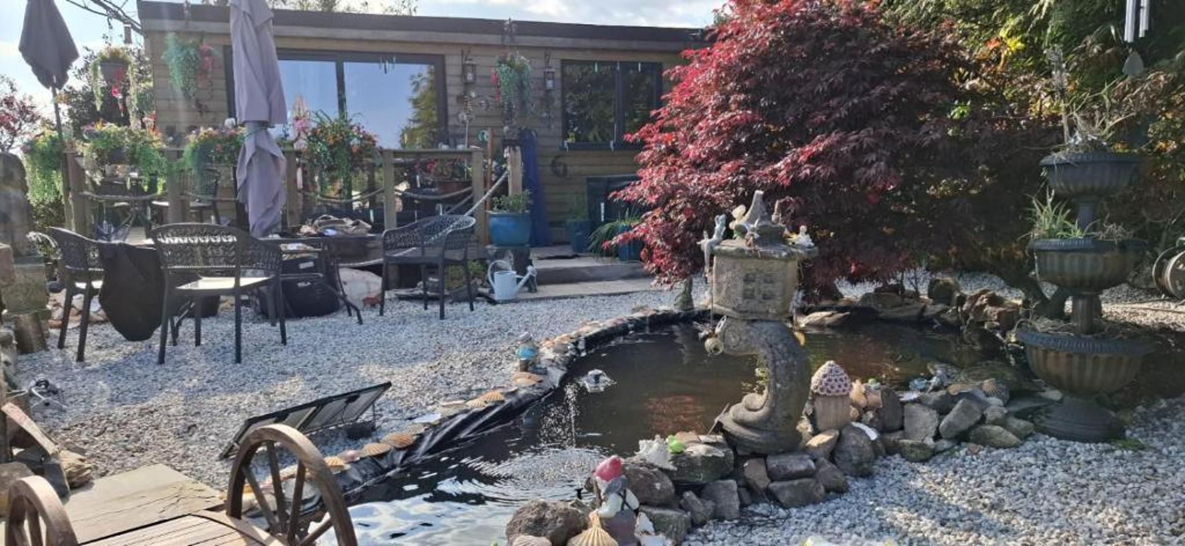 Un jardín con un estanque, una zona de estar y un edificio con ventanas.
