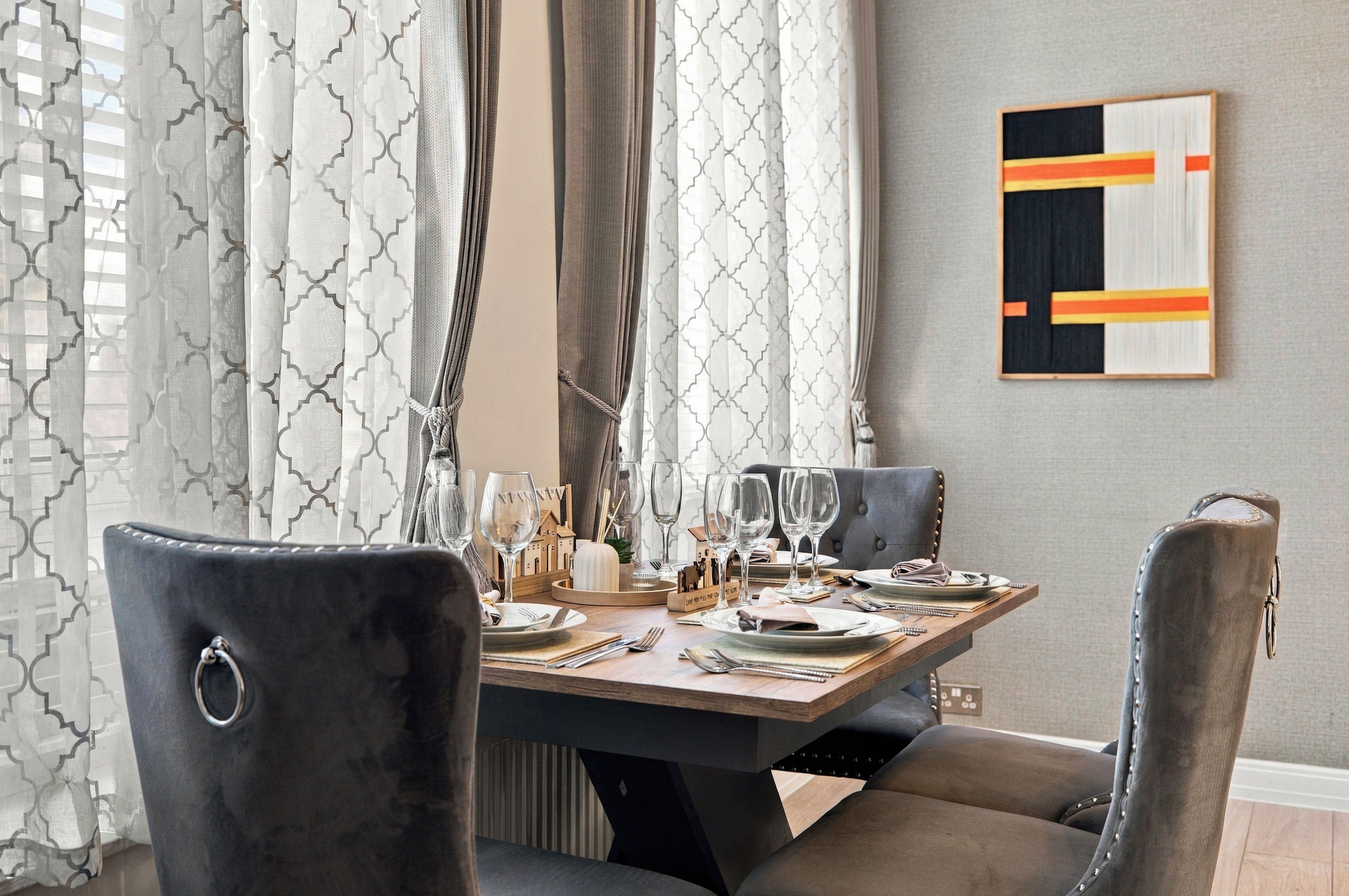 Comedor con una mesa lista para cuatro, con copas de vino, platos y cubiertos.