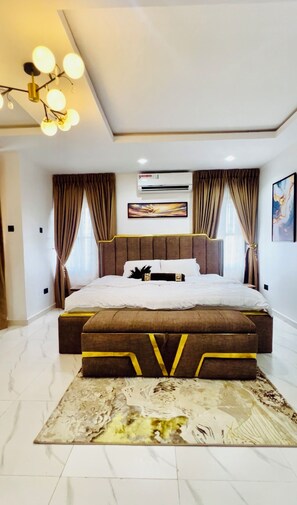 Une chambre moderne avec un grand lit, un luminaire au plafond, un appareil de climatisation et un tapis à motifs.