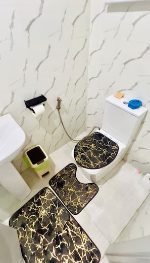 Une salle de bain équipée de toilettes, d’un bidet et d’une petite poubelle.