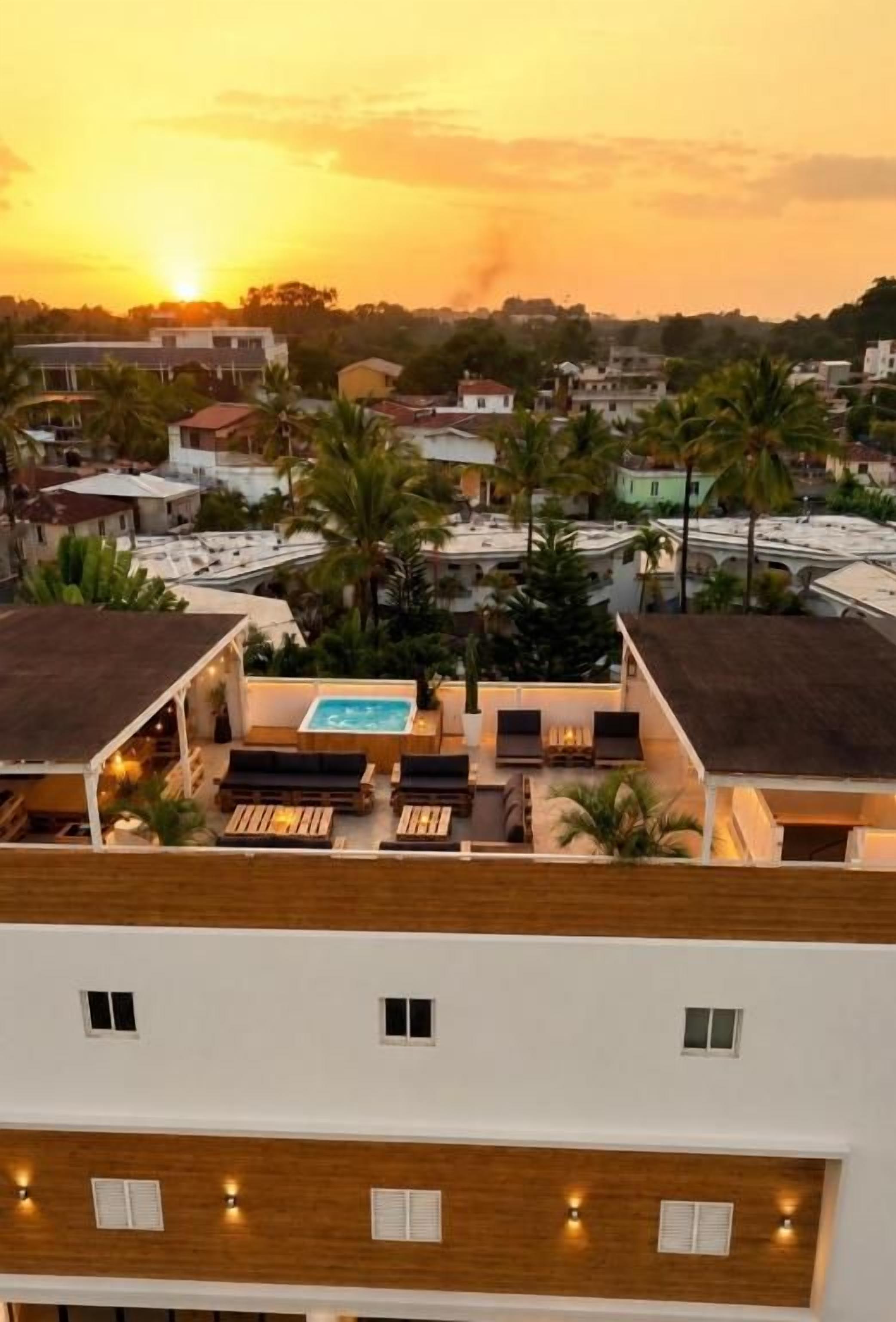 Una terraza con piscina, sillas de descanso y vistas a una zona residencial al atardecer.