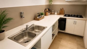 A modern kitchen with a double sink, a stove, and a window with a view of greenery.
