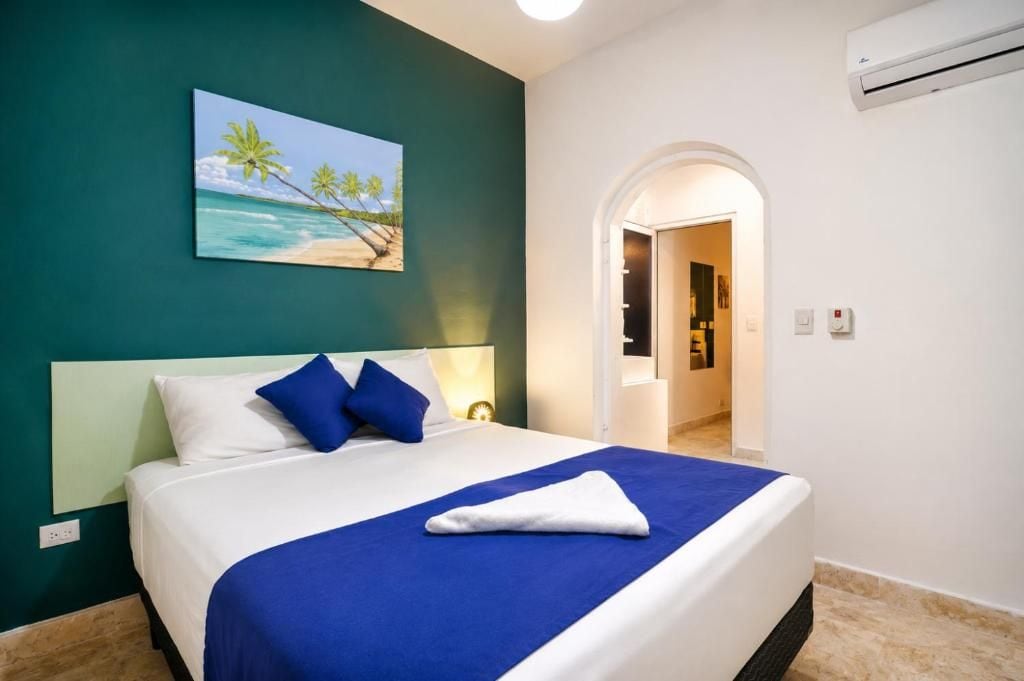 Habitación de hotel con cama, un cuadro de una playa y un equipo de aire acondicionado.