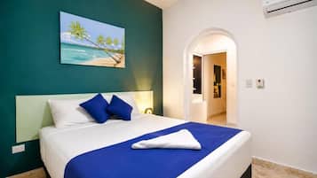 Habitación de hotel con cama, un cuadro de una playa y un equipo de aire acondicionado.