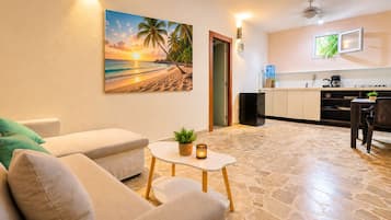 Una sala de estar con un sofá, una mesa de centro con una planta y un cuadro de una playa.