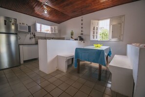 A compact kitchen with a refrigerator, microwave, and a table with a blue tablecloth. - Casa com Piscina a 400m da Enseada dos Corais (Cabo de Santo Agostinho)