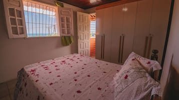 A bedroom with a bed, a window with bars, and a wardrobe.