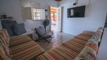 A living room with striped sofas, a chair, a TV, and a fan.