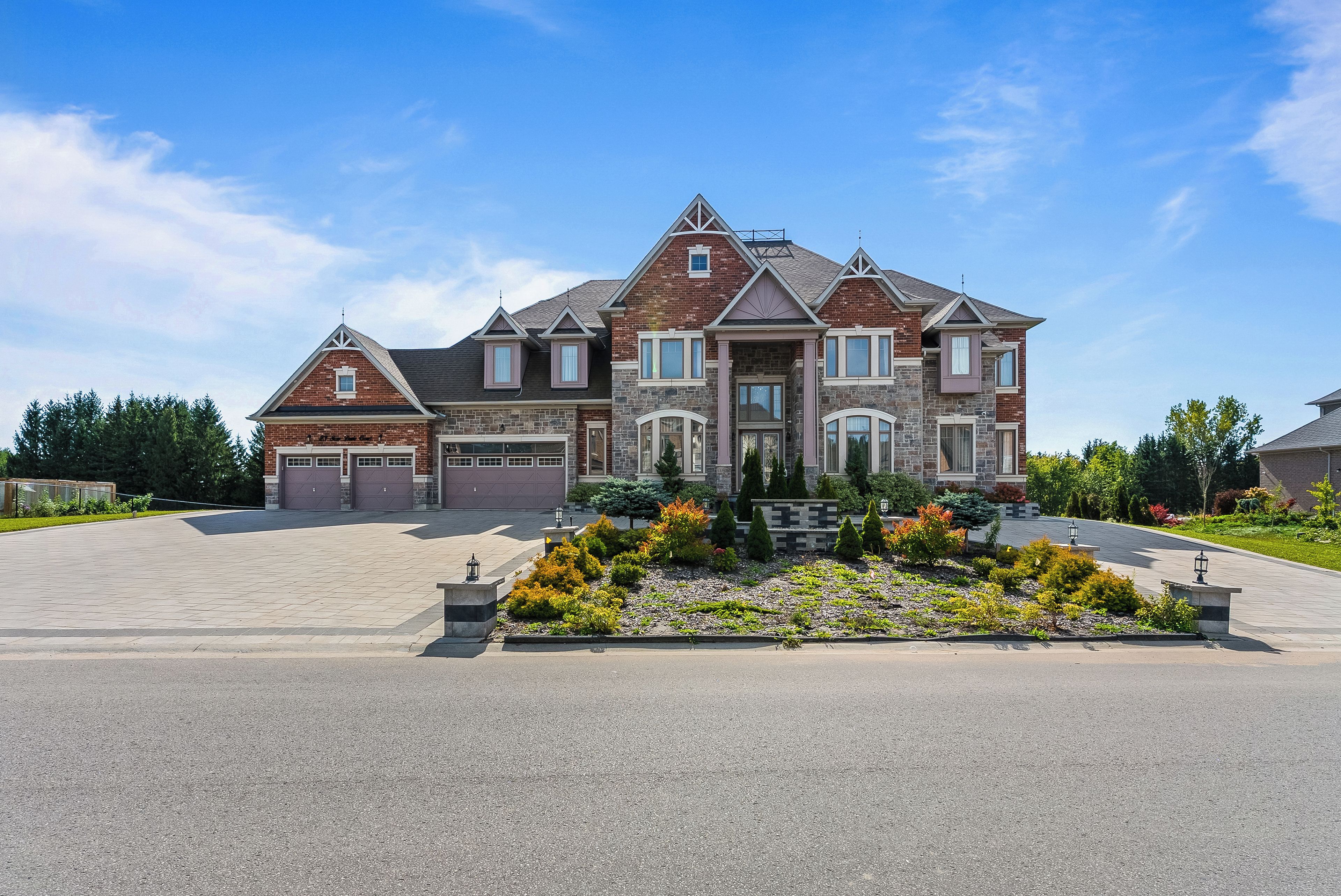 A large, two-story house with a garage, a driveway, and a landscaped front yard.