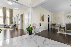 Amplia sala de estar con piso de mármol, un conjunto de sofás, una mesa de centro y una planta en maceta.