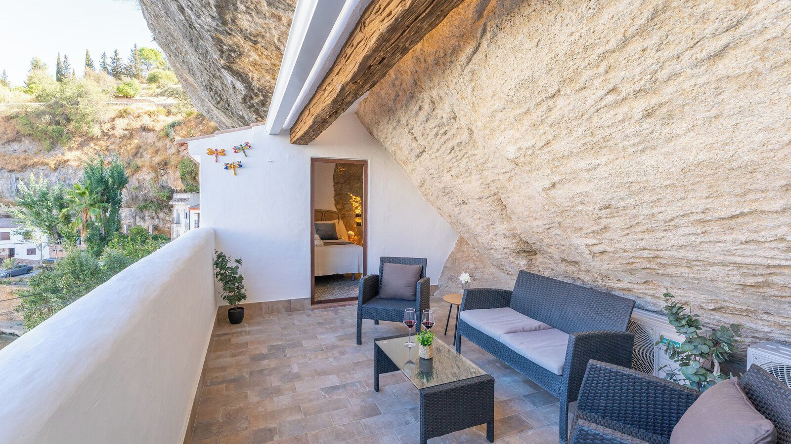 Un balcon aménagé avec du mobilier d’extérieur, une vue sur les environs et une porte donnant sur un espace intérieur.