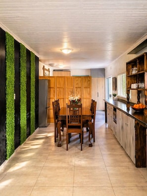 A modern kitchen with a dining area, featuring a wooden table and chairs, a built-in oven, and a green vertical garden. - Hansoty Airbnb Ivypark Polokwane (Polokwane)