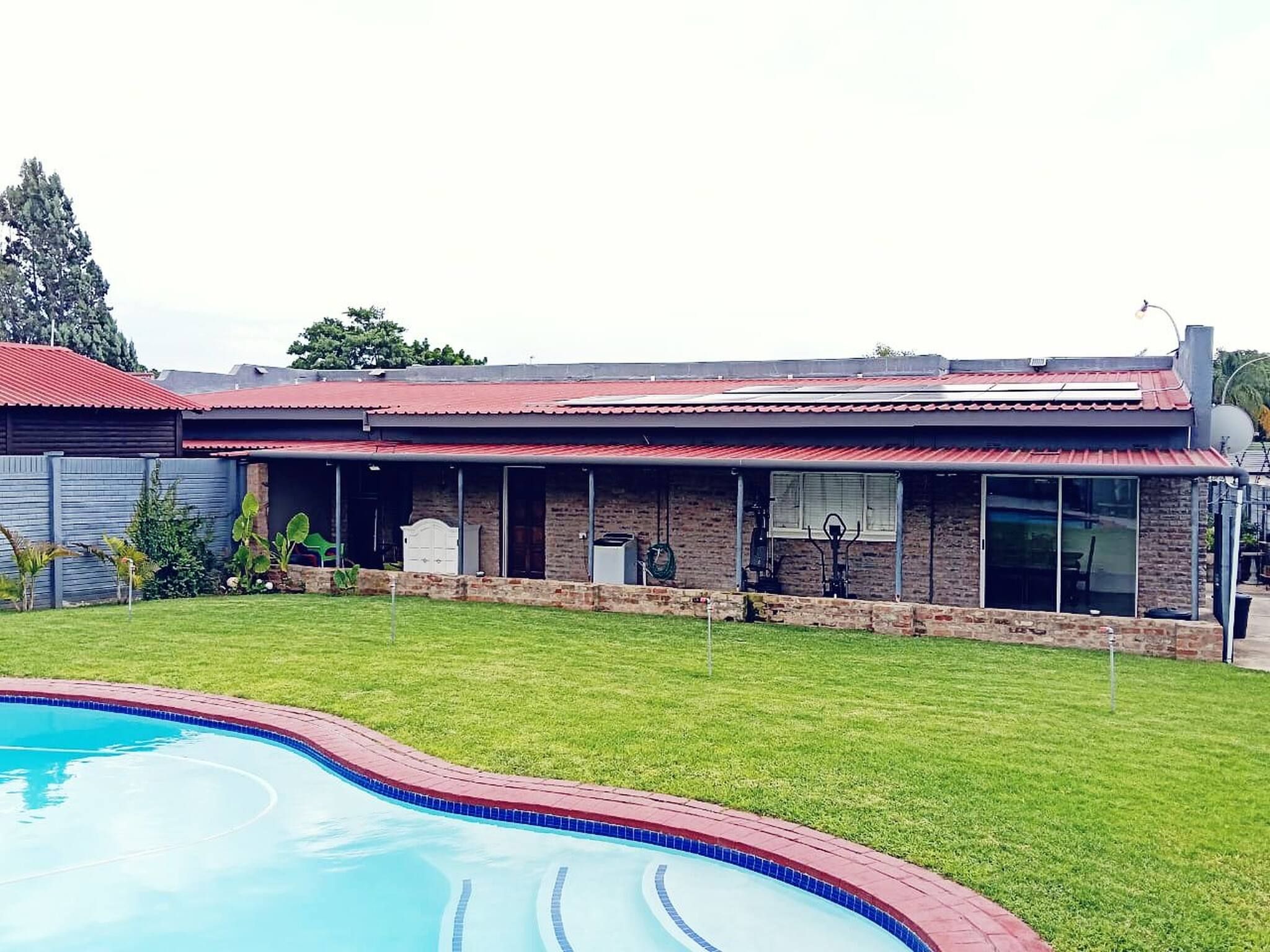 A residential property with a swimming pool, a covered patio, and a brick exterior.