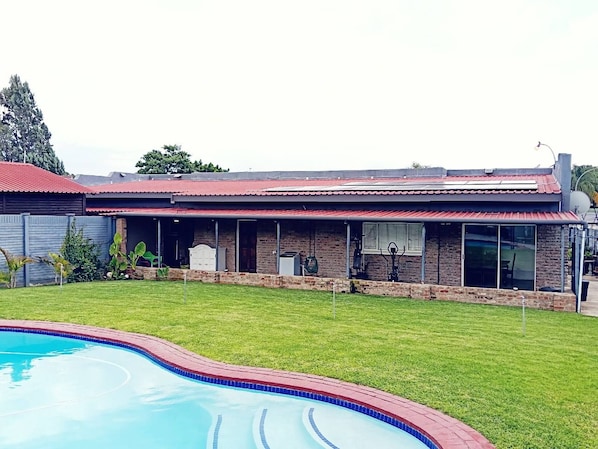 A residential property with a swimming pool, a covered patio, and a brick exterior. - Hansoty Airbnb Ivypark Polokwane (Polokwane)