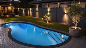 A swimming pool with a curved edge, surrounded by a brick patio. - Hansoty Airbnb Ivypark Polokwane (Polokwane)