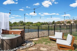 Una vasca idromassaggio con un prendisole e un'area recintata con decking in legno.