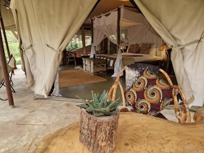 Alojamiento en carpa con cama, una mesa y una planta en maceta.