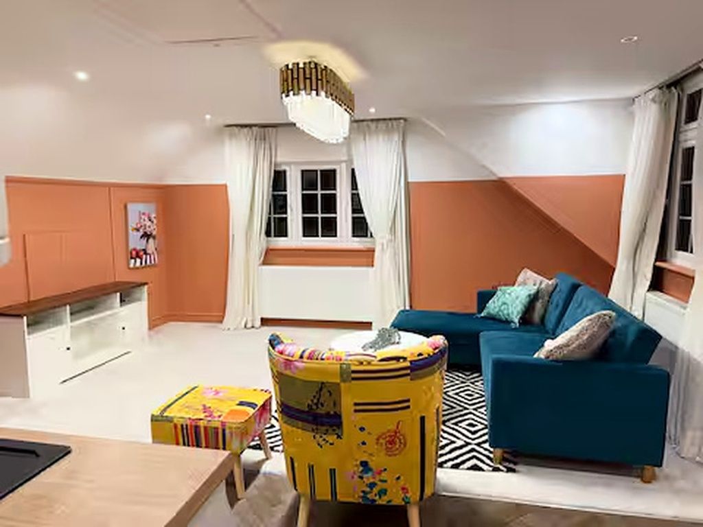 A living room with a sofa, a small table, a chair, and a window with curtains.