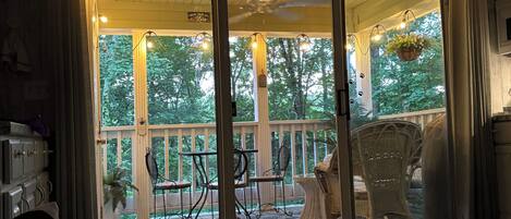 A room with a sliding glass door leading to an outdoor patio area with wicker furniture and a view of trees.