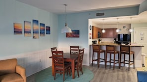 Una cocina moderna con armarios de madera, un comedor con mesa y sillas, y una sala de estar con sofá.