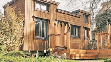 Eine Holzhütte mit mehreren Fenstern, einer Holzdiele und einem Garten mit Tulpen.