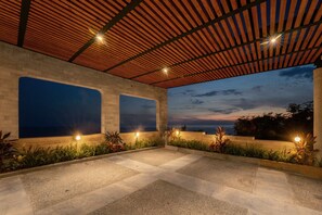 Een buitenpatio met een pergola, grote ramen en decoratieve verlichting.