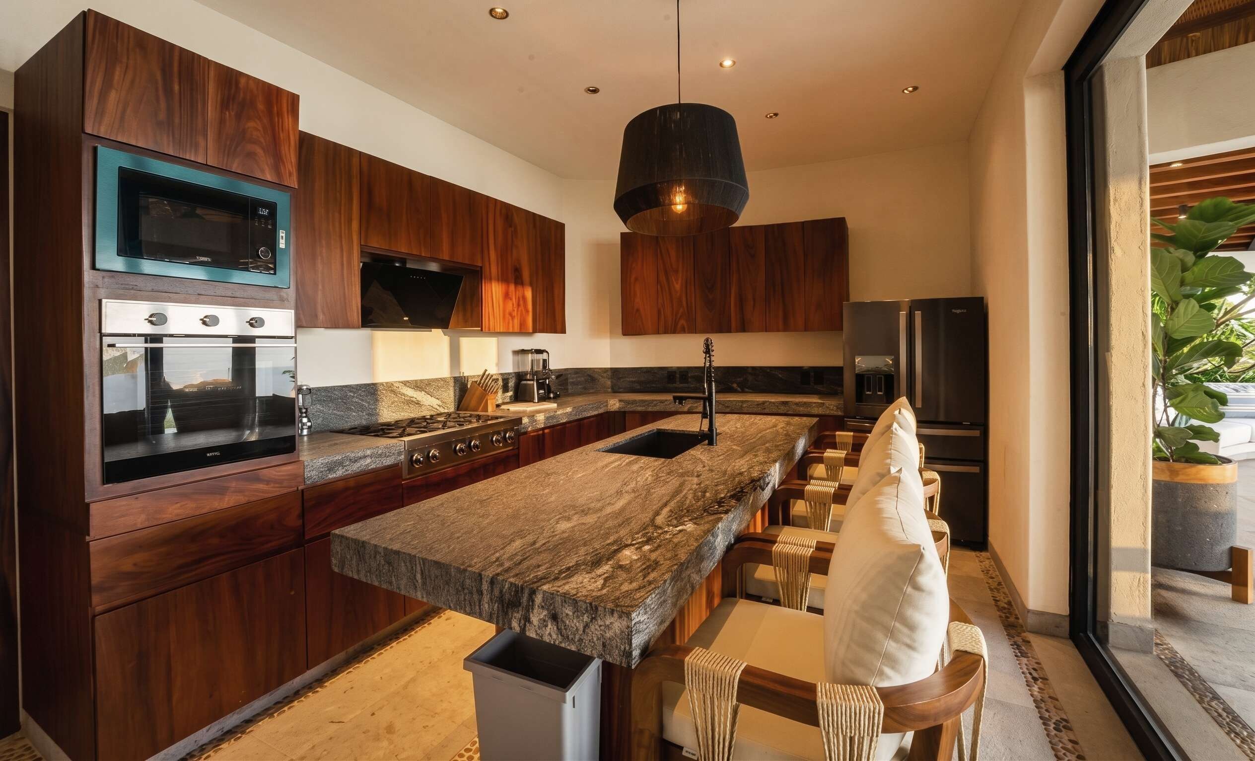 A modern kitchen with wooden cabinets, a granite countertop, a built-in oven, a microwave, a coffee maker, and a sink.