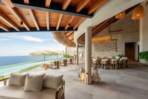 Ampla área externa com piscina, assentos e vista para o oceano.