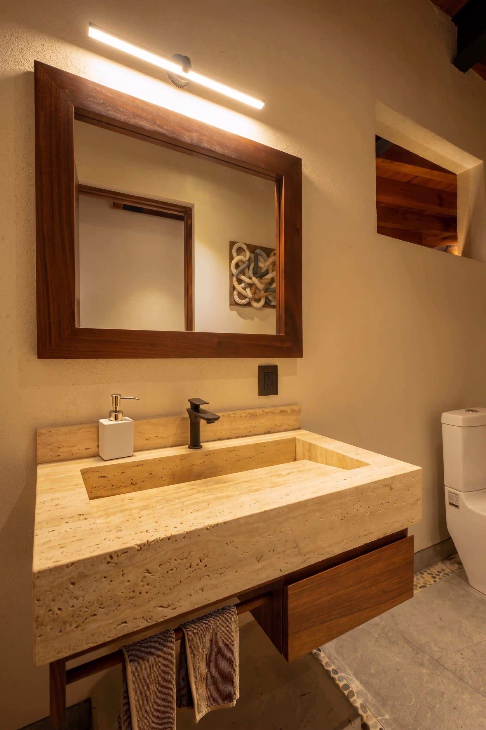 A bathroom with a wooden vanity, a large mirror, a towel rack, and a toilet.