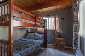 Quarto com beliche, mesa de cabeceira e luminária.